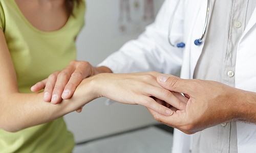 A doctor checking the hands and wrist of a patient