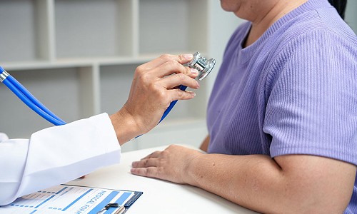 A doctor about to place a stethoscope on a patient wearing a blue t-shirt